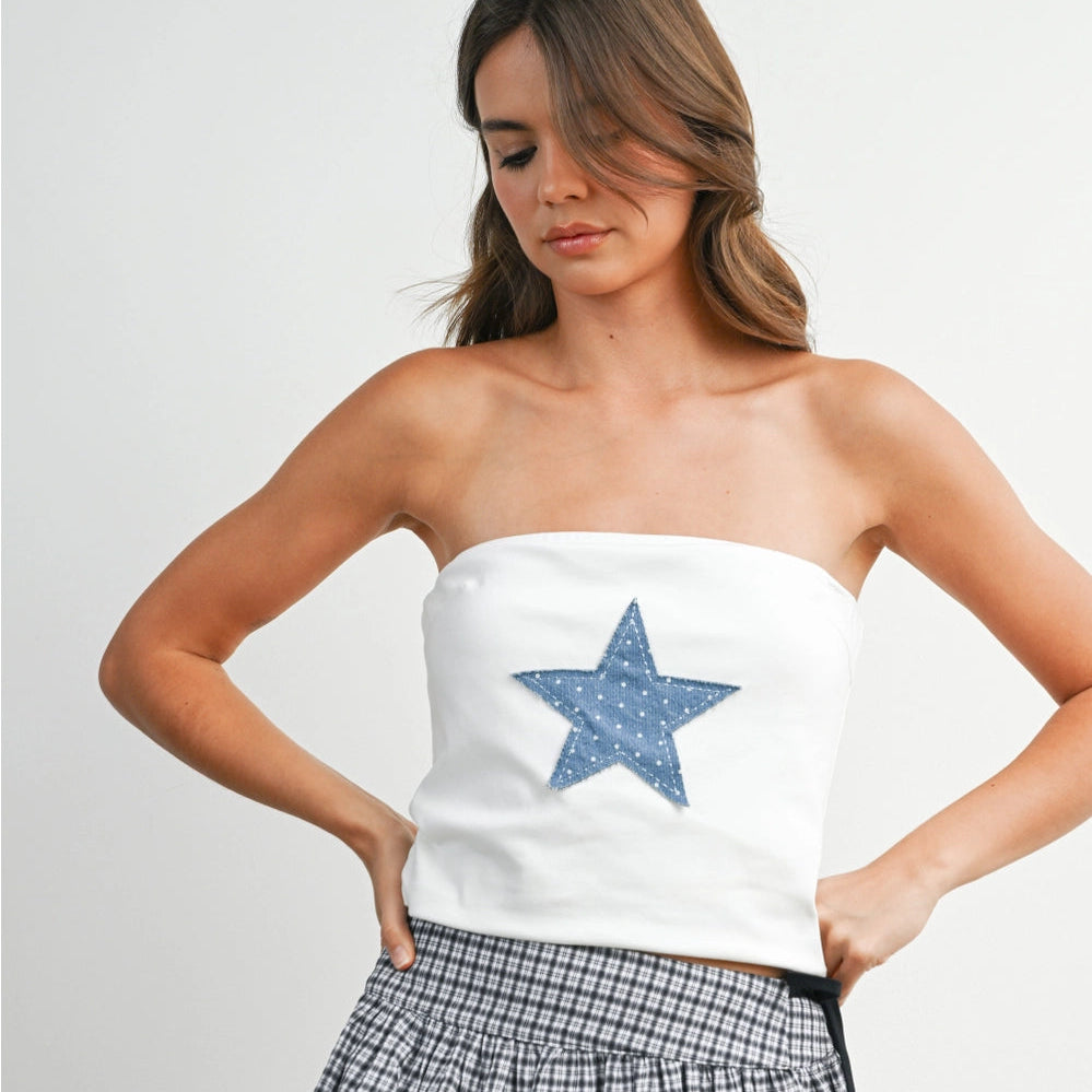 Woman wearing a strapless top with a blue star and a plaid skirt on a white background