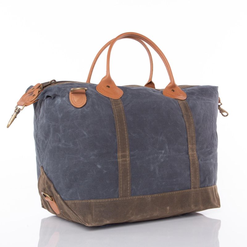 Blue waxed canvas duffel bag with brown leather accents on a white background