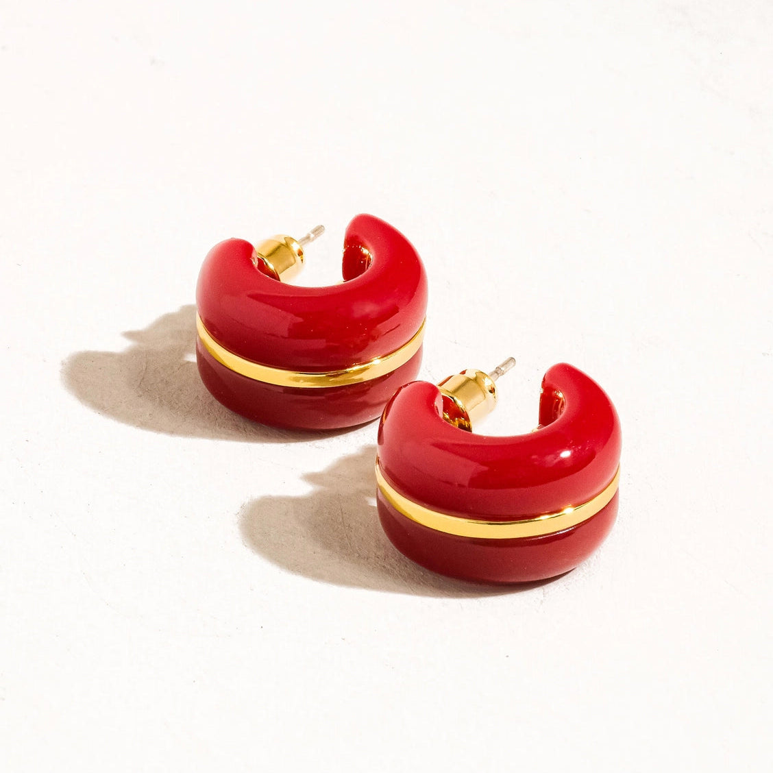 Red hoop earrings with gold accents on a white background
