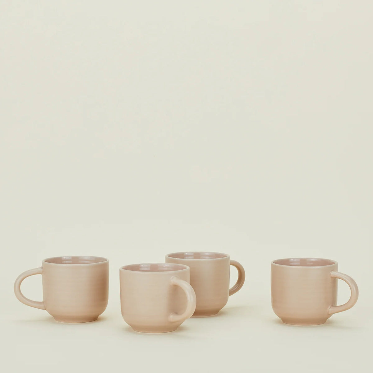 Four pink mugs on a light beige background
