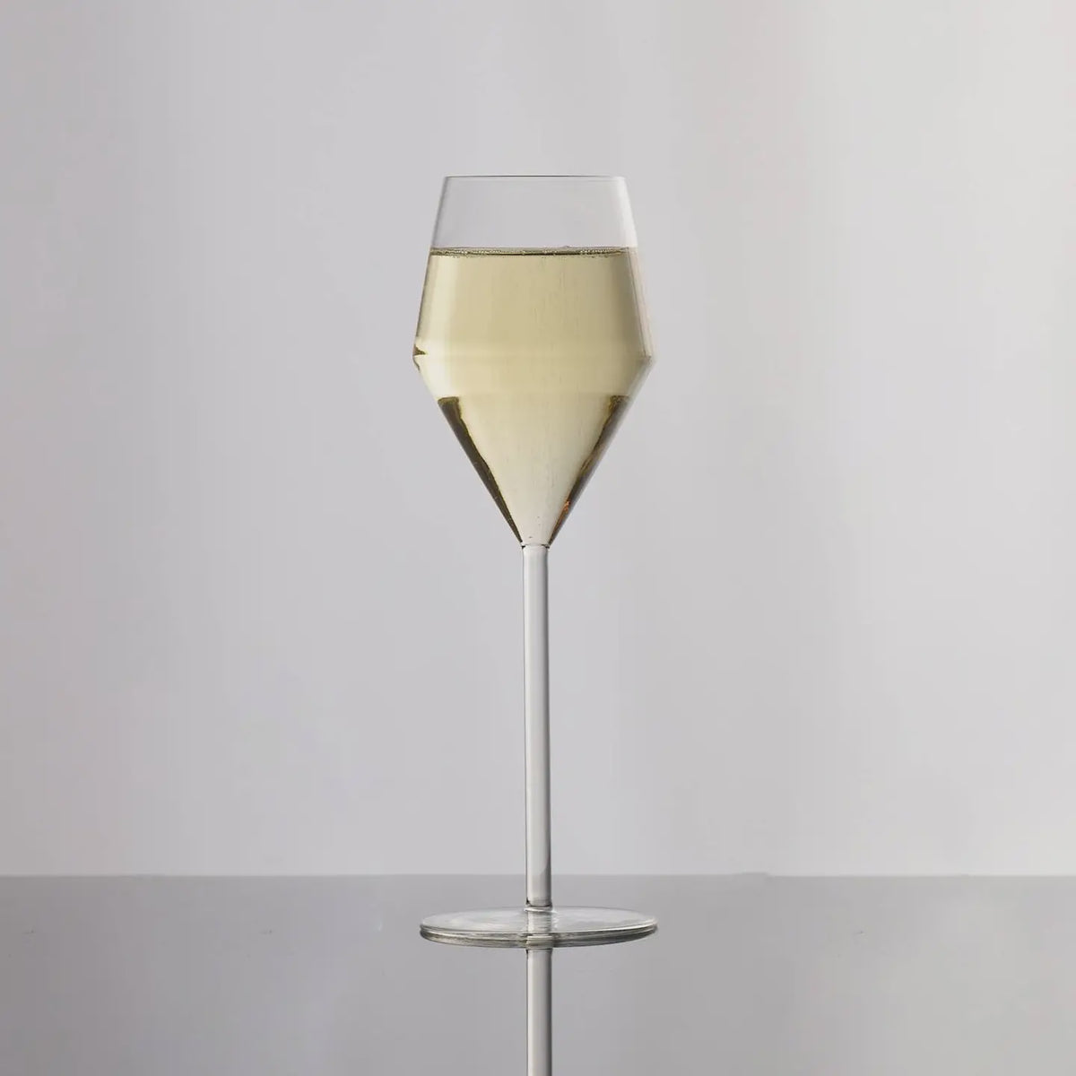 Clear wine glass with white wine on a gray background