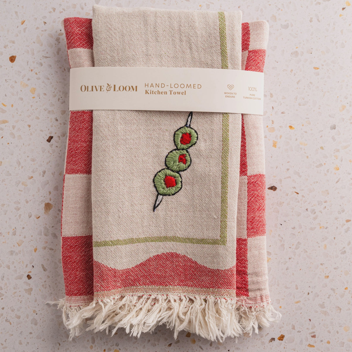Hand-loomed kitchen towel with embroidery on a textured surface