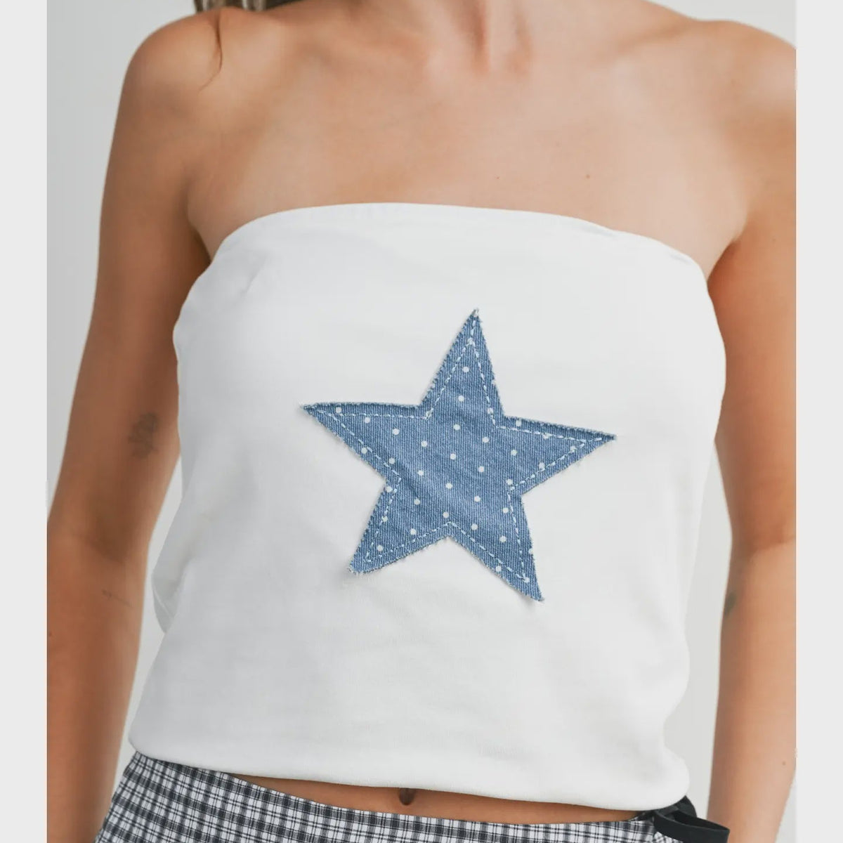 White strapless top with a blue star design worn by a person.