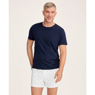 Man wearing a navy t-shirt and white patterned shorts on a beige background
