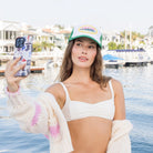 Woman taking a selfie by a waterfront with boats in the background