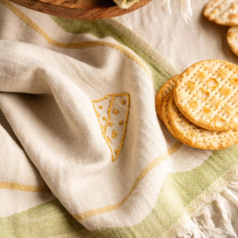 Decorative towel with embroidered design and crackers on a wooden surface