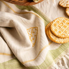 Decorative towel with embroidered design and crackers on a wooden surface