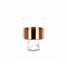 A clear low ball glass with hand-painted copper detailing on the inside, presented against a white background.