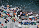 Outdoor seating area with colorful chairs and umbrellas by a waterfront.