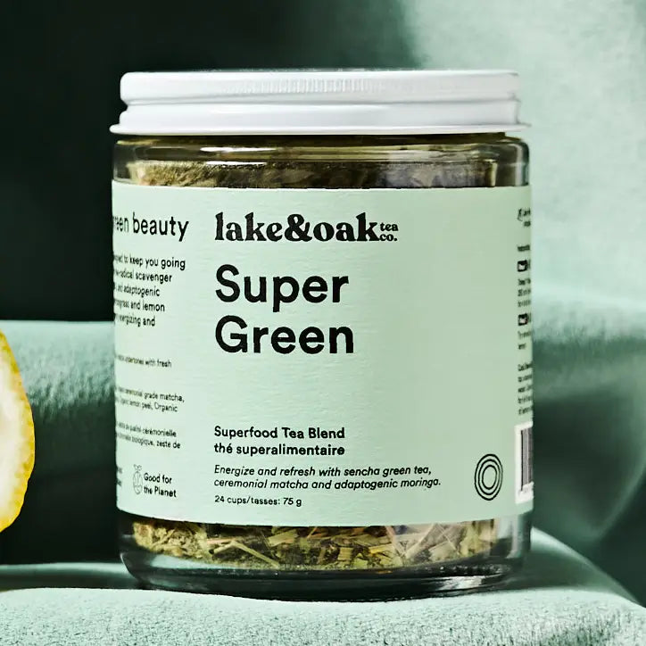 Jar of 'Super Green' tea blend with 'lake&oak tea co.' label on a green surface.