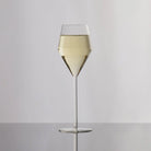 Clear wine glass with white wine on a gray background