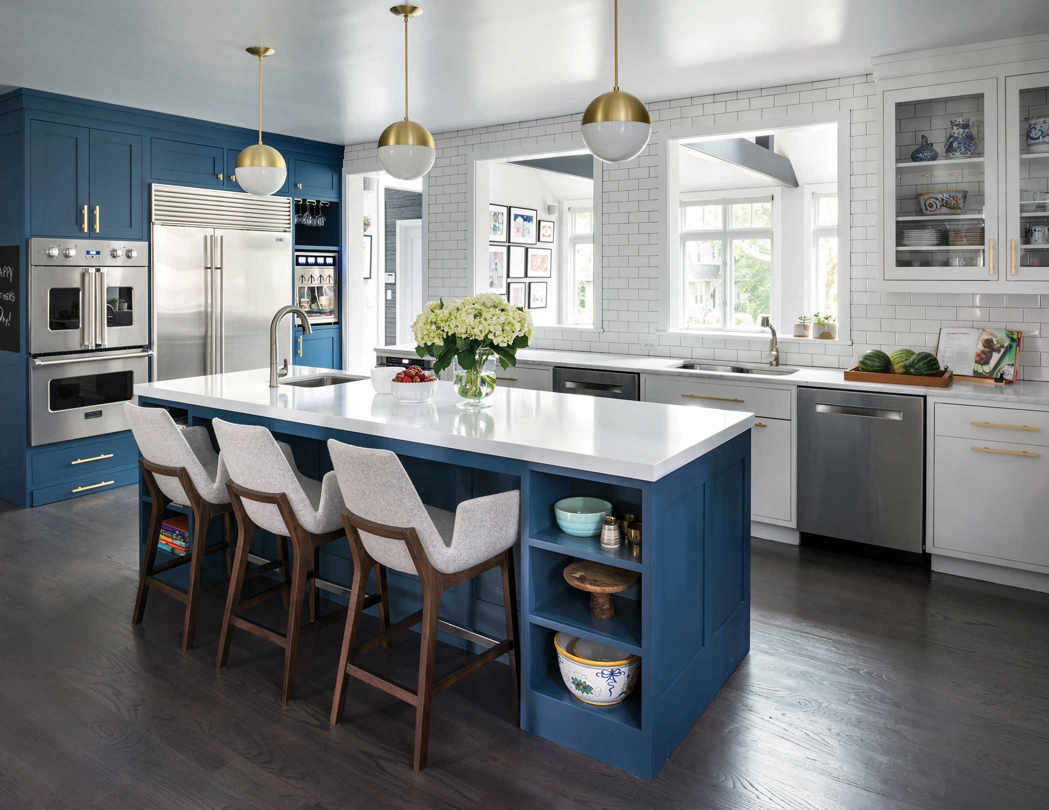 A kitchen designed by Studio Dearborn with blue counters and white chairs