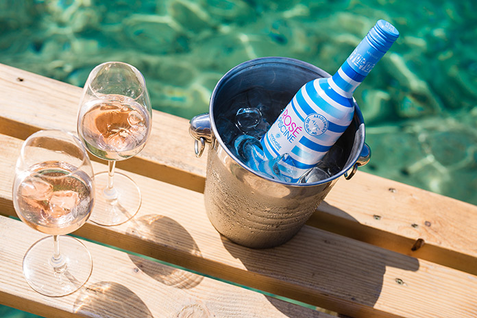 Bucket of rosé next to two glasses of rosé on the rocks